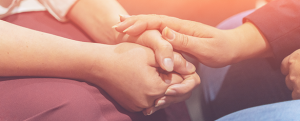 A psychologist holds her hand over the clients hand in comfort.